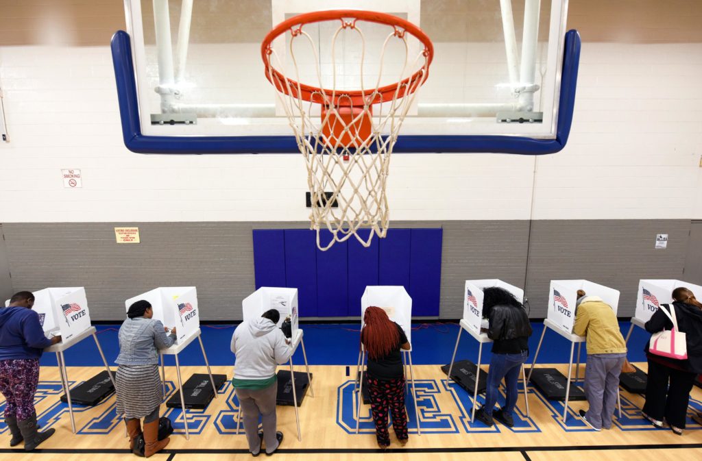 Seven people vote on a basketball court at a recreation center serving as polling place.