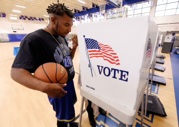 A man holds his basketball while receiving assistance from an election official at a recreation center serving as polling place.